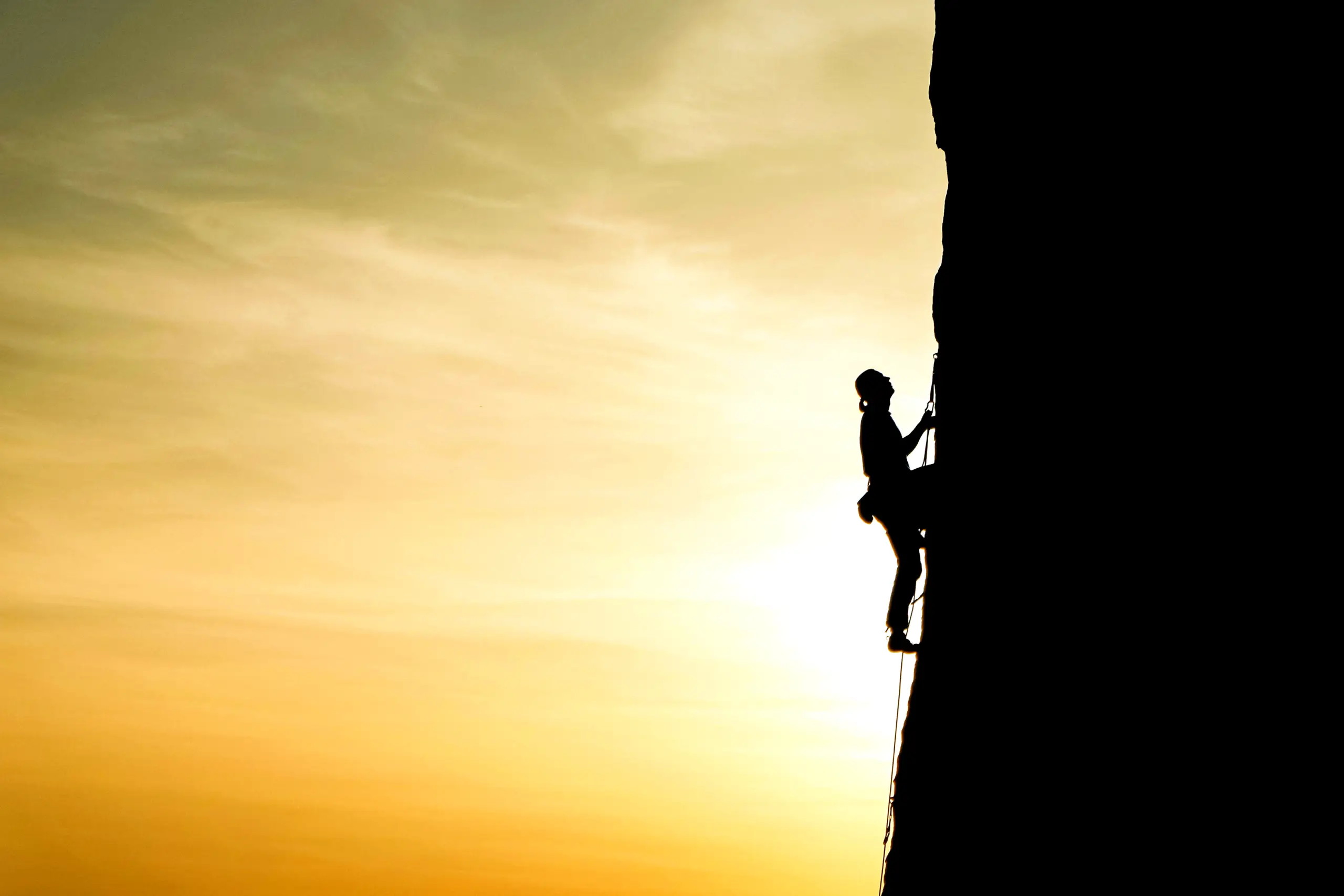 Illustration symbolisant le défi de l'arrêt du tabac avec un homme gravissant une montagne abrupte au lever du soleil
