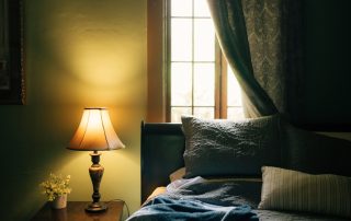 Chambre feutrée avec lampe de chevet allumée pour un article sur la qualité de votre sommeil