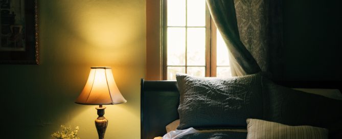 Chambre feutrée avec lampe de chevet allumée pour un article sur la qualité de votre sommeil